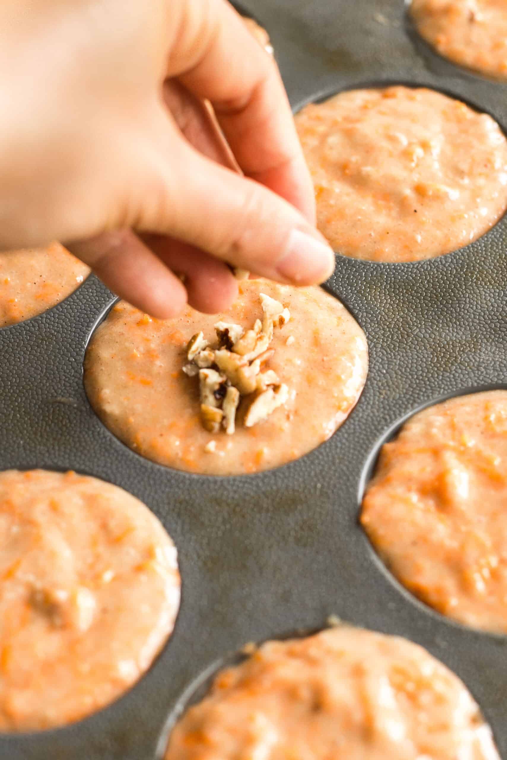 Topping carrot muffin batter with chopped pecans.