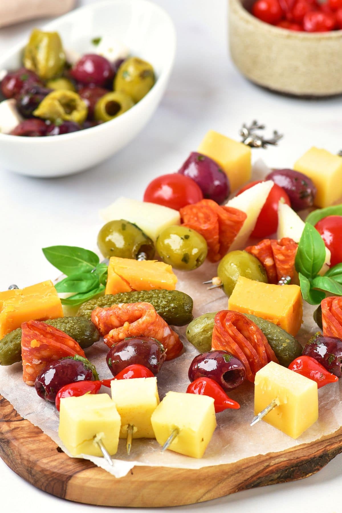 Antipasto skewers on parchment-lined wooden board.
