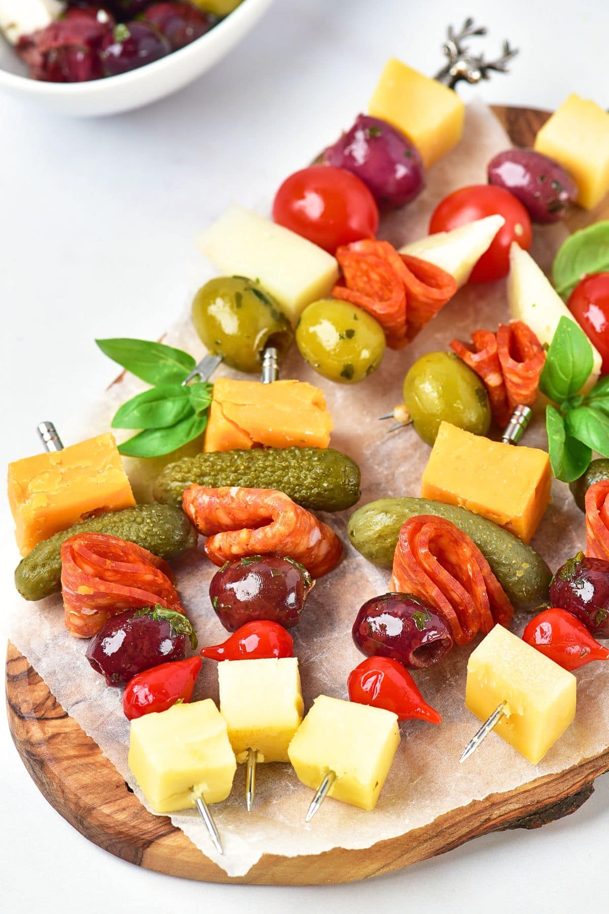 Charcuterie skewers on parchment-lined wooden board.
