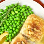 Top down view of a plate of chicken cordon bleu and green peas