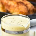 Up close view of gluten-free chicken gravy in front of a pan of roasted chicken.