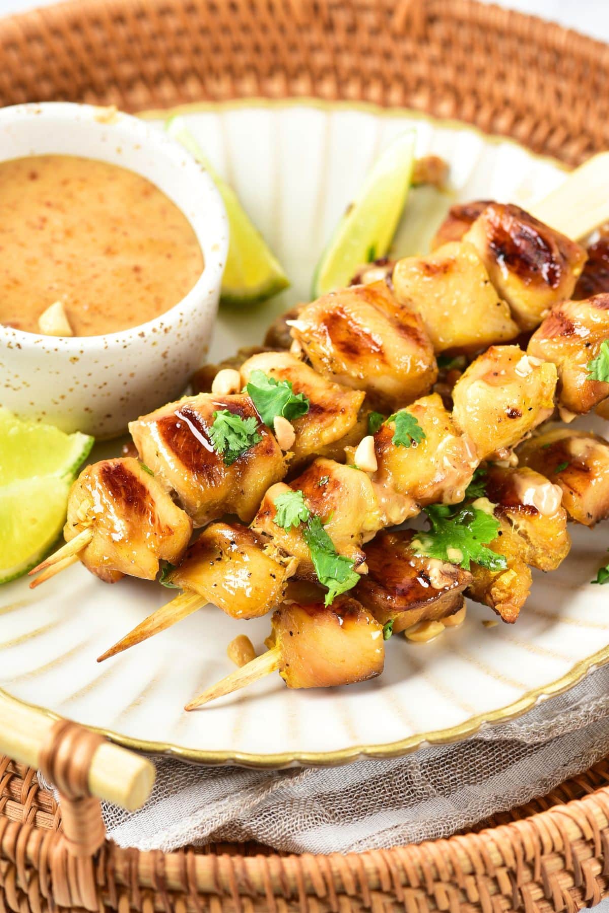 A plate of satay chicken skewers on bamboo tray