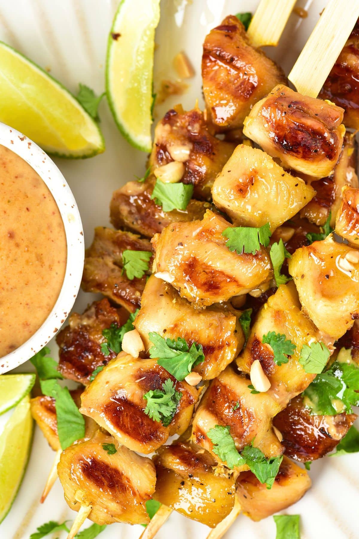 Up close view of chicken satay skewers with peanut sauce.