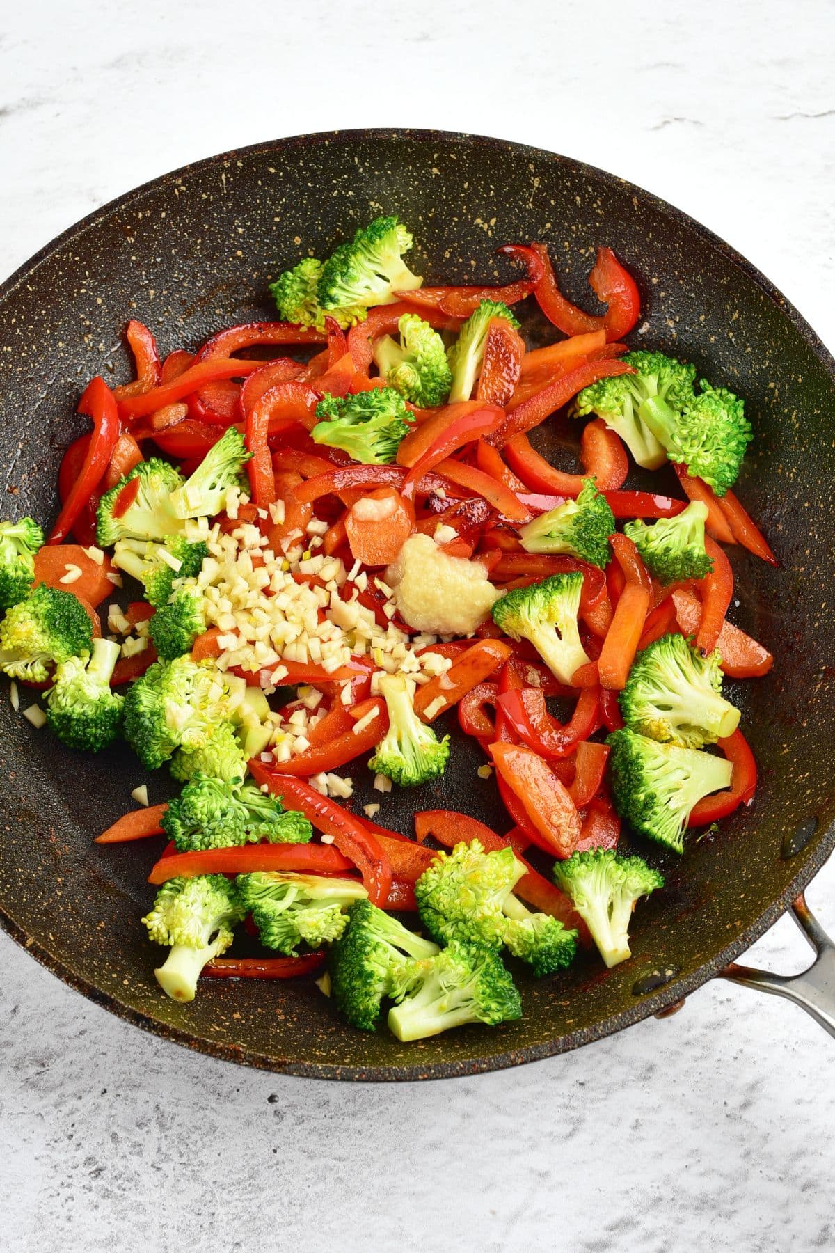 Raw broccoli, bell peppers, garlic and ginger in a skillet