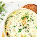 Top down view of a bowl of wild rice chicken soup on wooden board