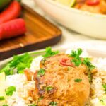 A plate with white rice topped with coconut and lime chicken