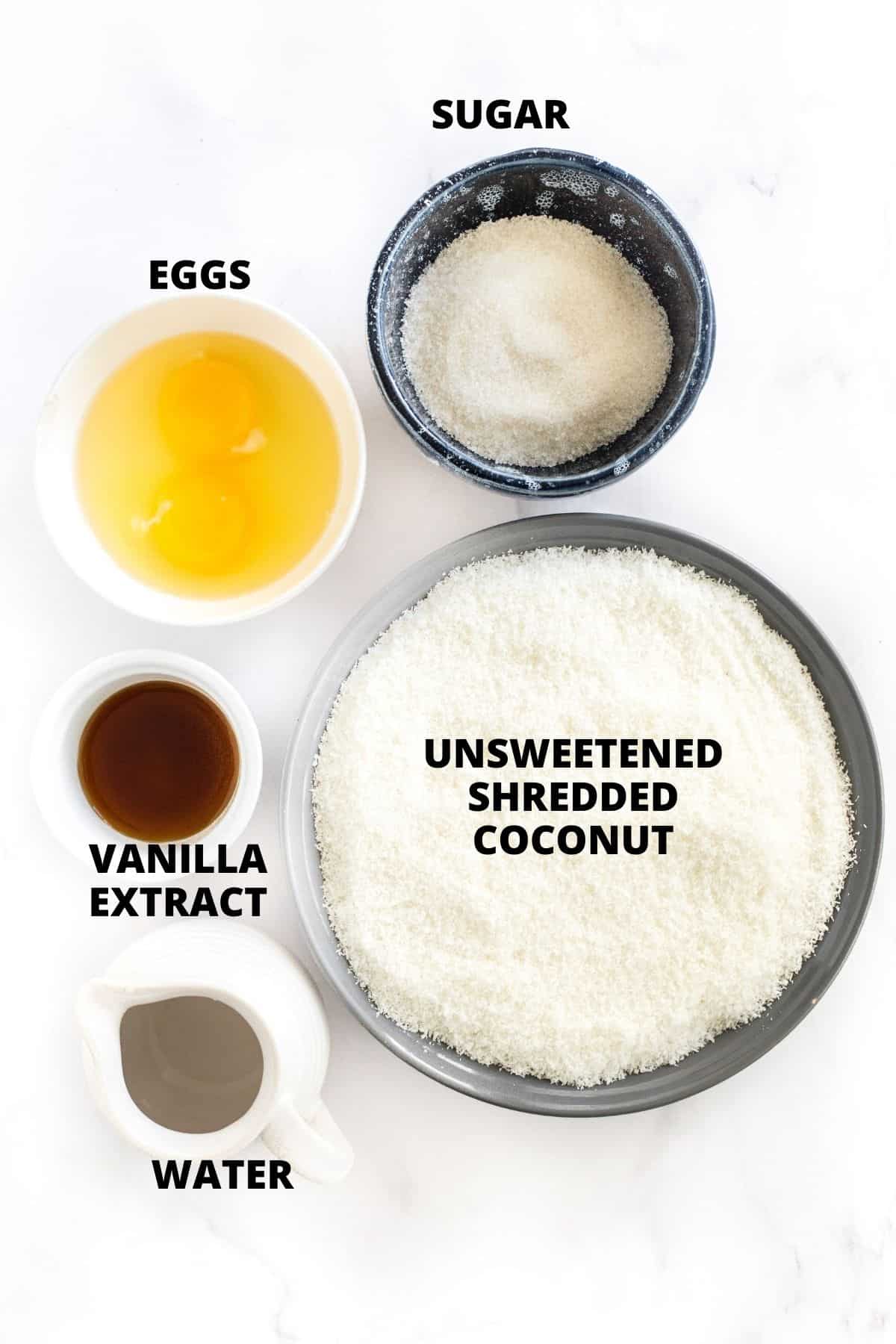 Labeled ingredients for gluten-free coconut macaroons laid out on a marble board.