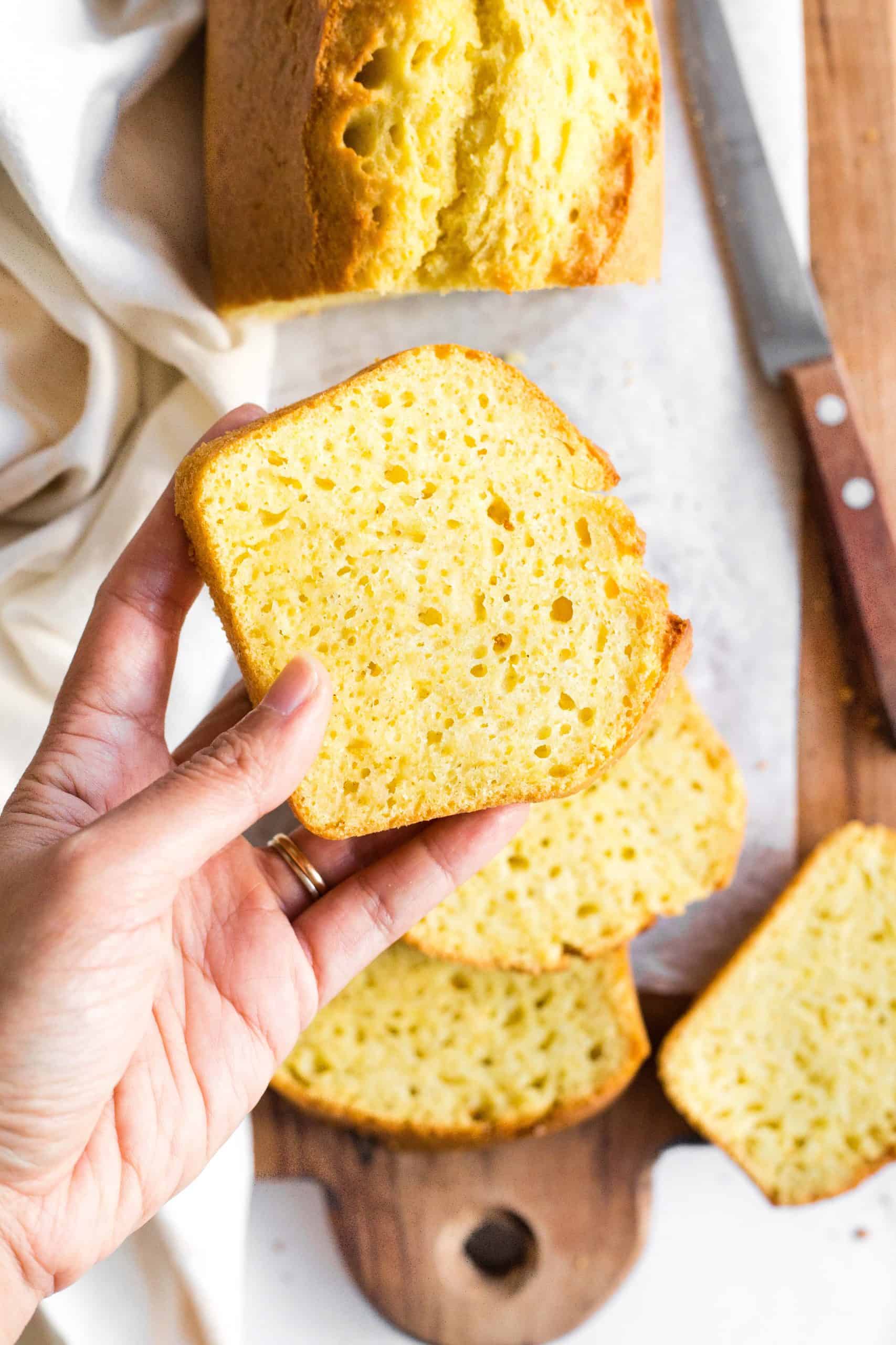 Hand holding up a slice of corn bread.