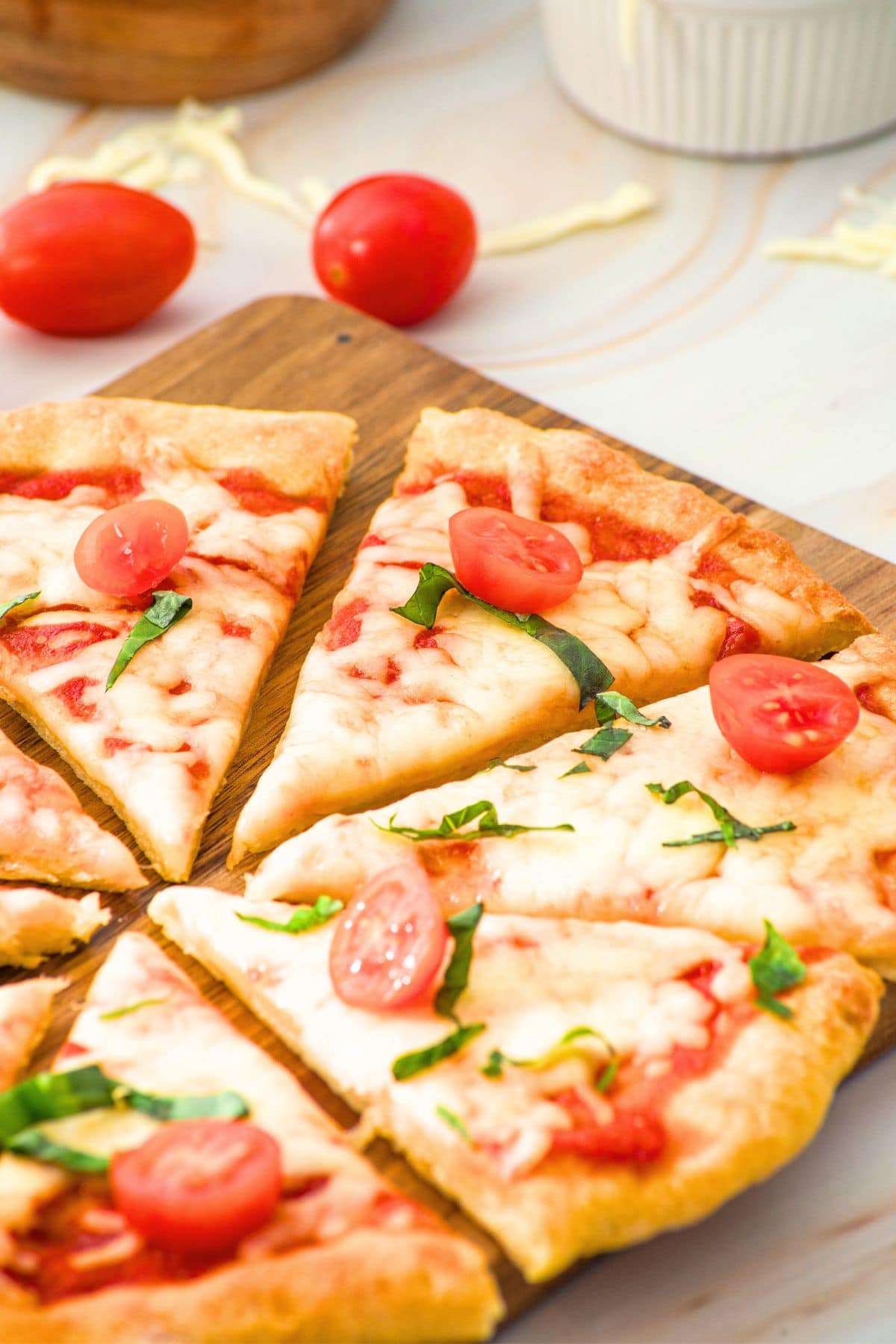 Sliced pizza topped with basil and tomatoes