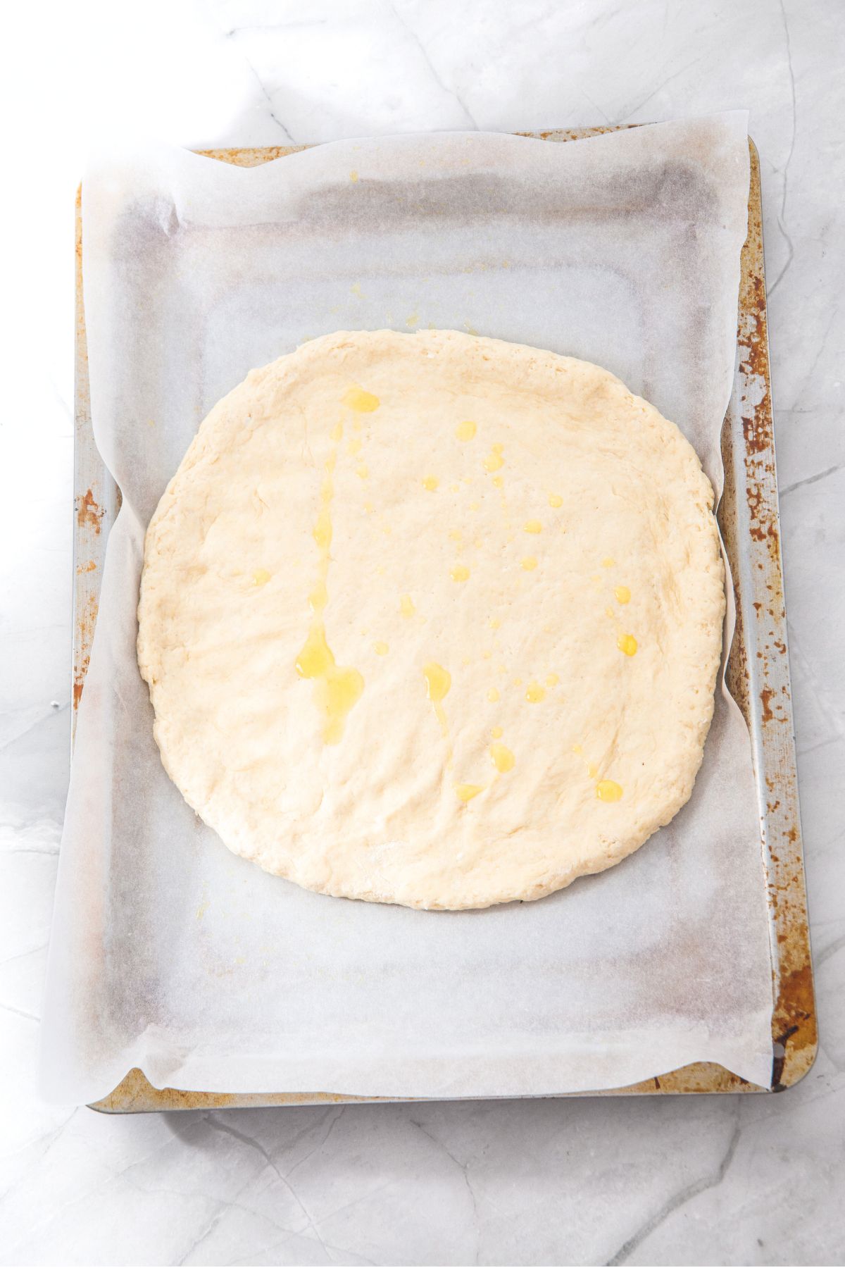 Olive oil brushed on top of pizza dough