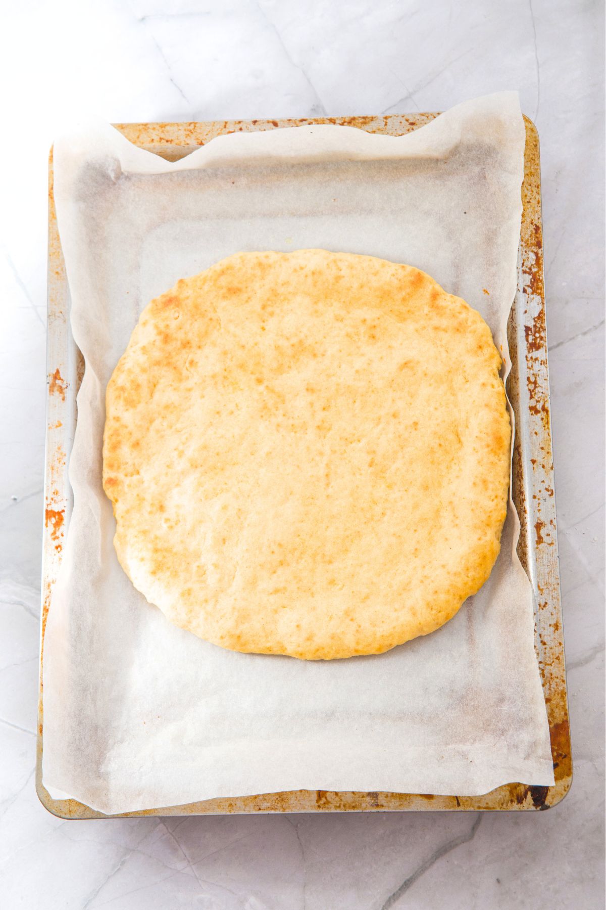 Freshly baked pizza crust on baking sheet