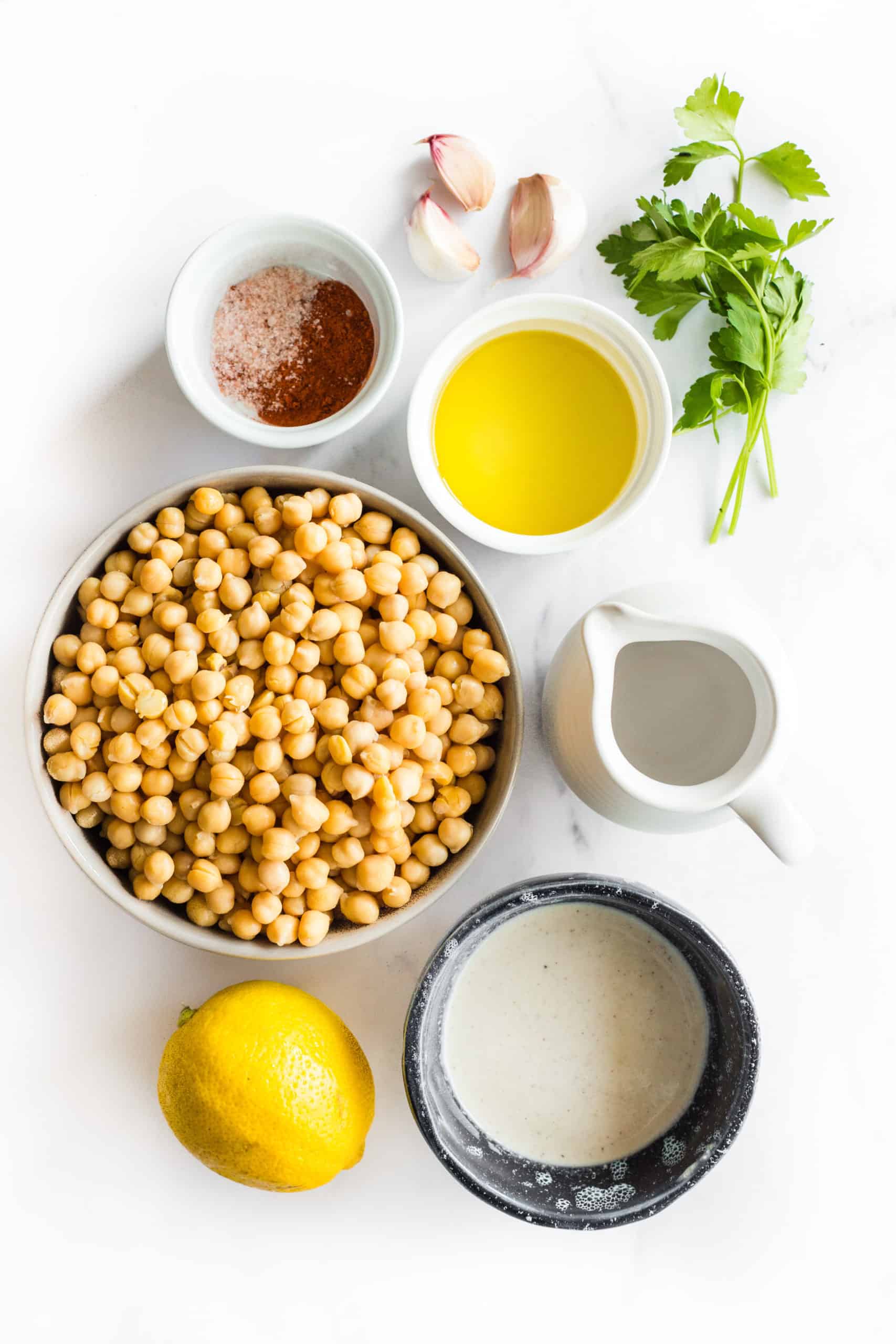 Ingredients for preparing hummus - chickpeas, garlic, tahini, lemon, water, parsley, salt and paprika.