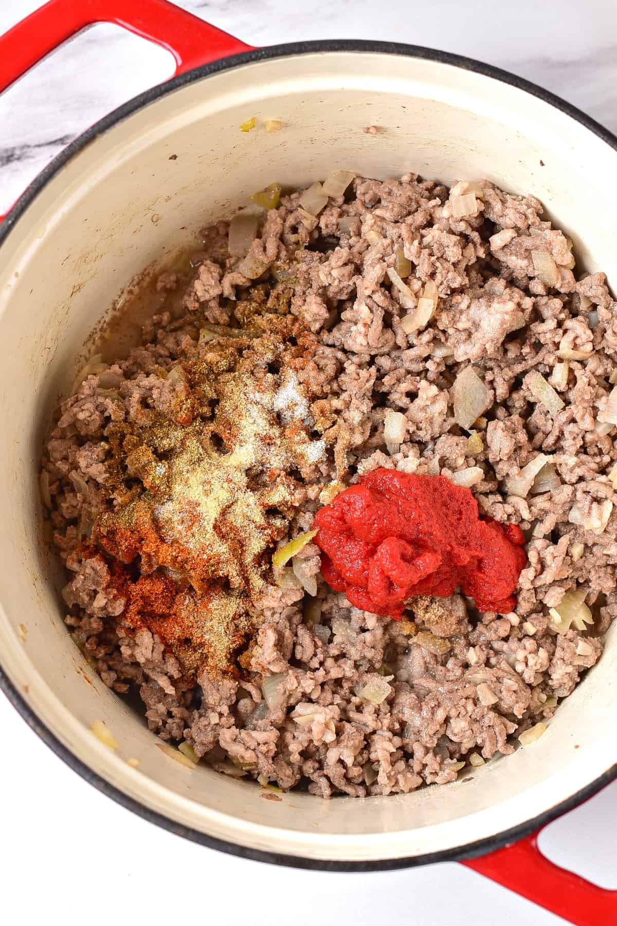 Cooked ground beef and tomato paste in a pot.
