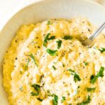 Top down view of a bowl of egg salad garnished with chopped parsley.