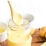 Spoon drizzling garlic aioli into a jar.