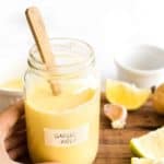 Hand holding a jar of garlic aioli.