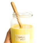 Hand holding a jar of garlic aioli.