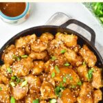 A skillet of General Tso's chicken sprinkled with green onions