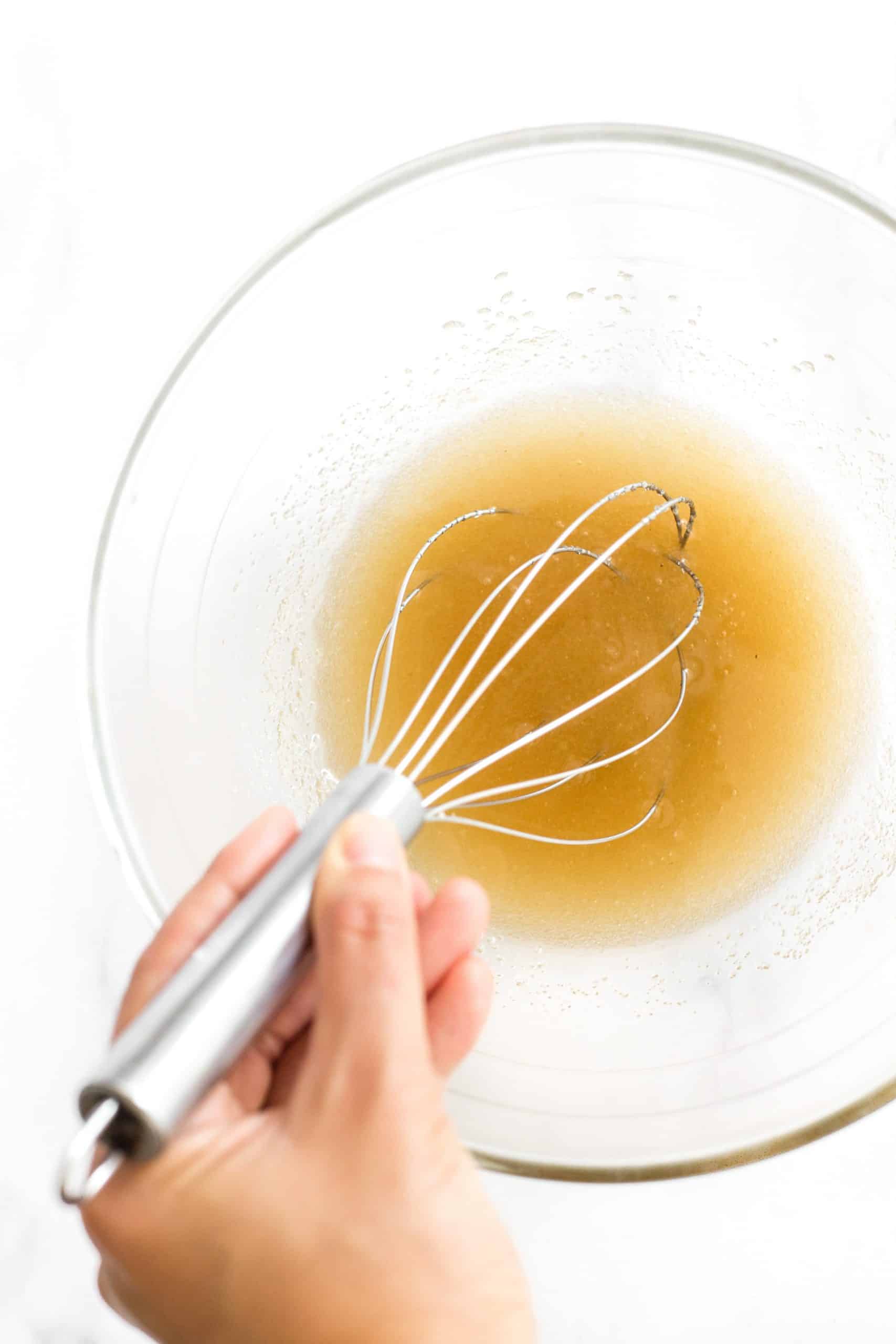 Creaming sugar and oil in a glass mixing bowl.
