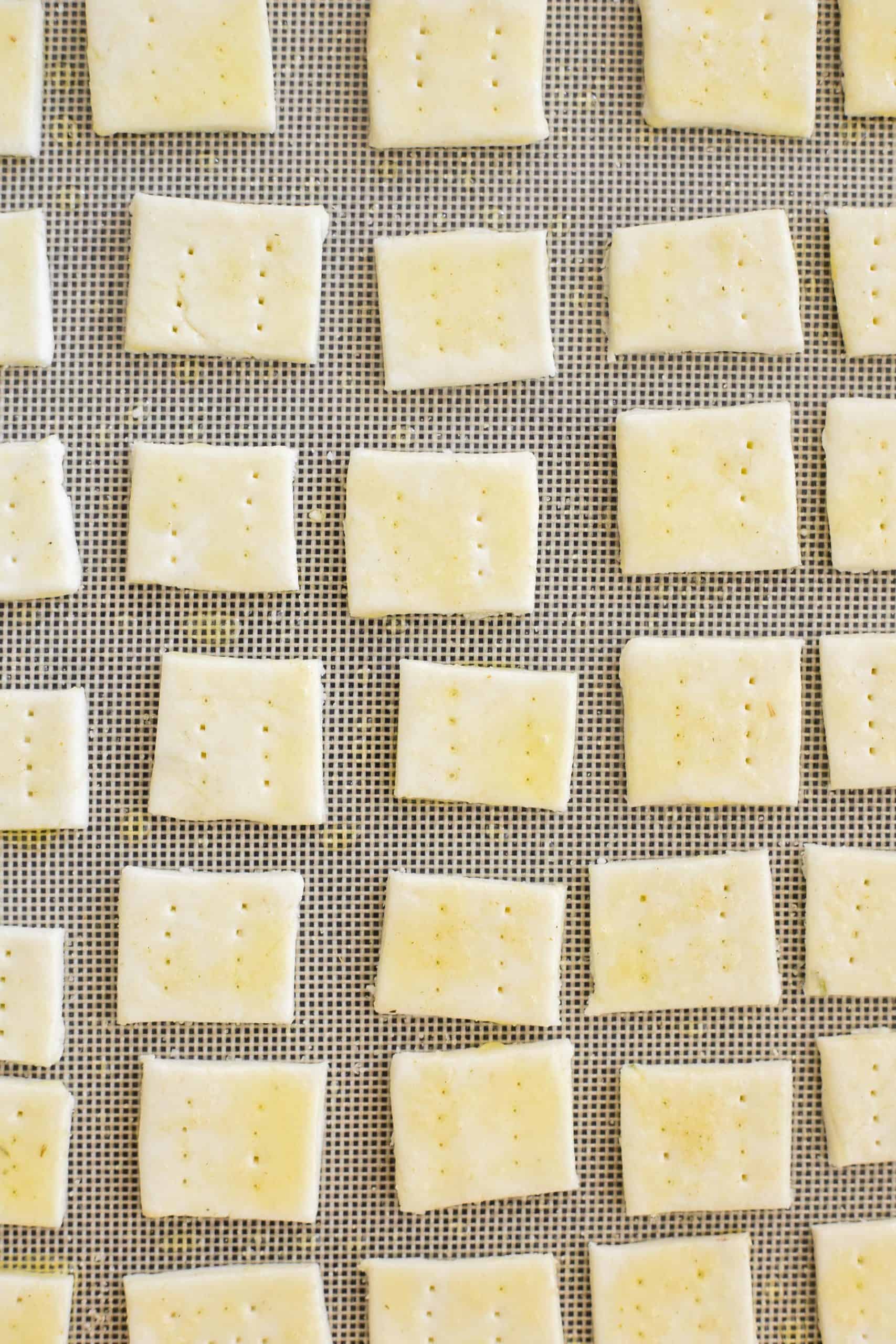 Cracker dough squares on a silpat-lined baking sheet.