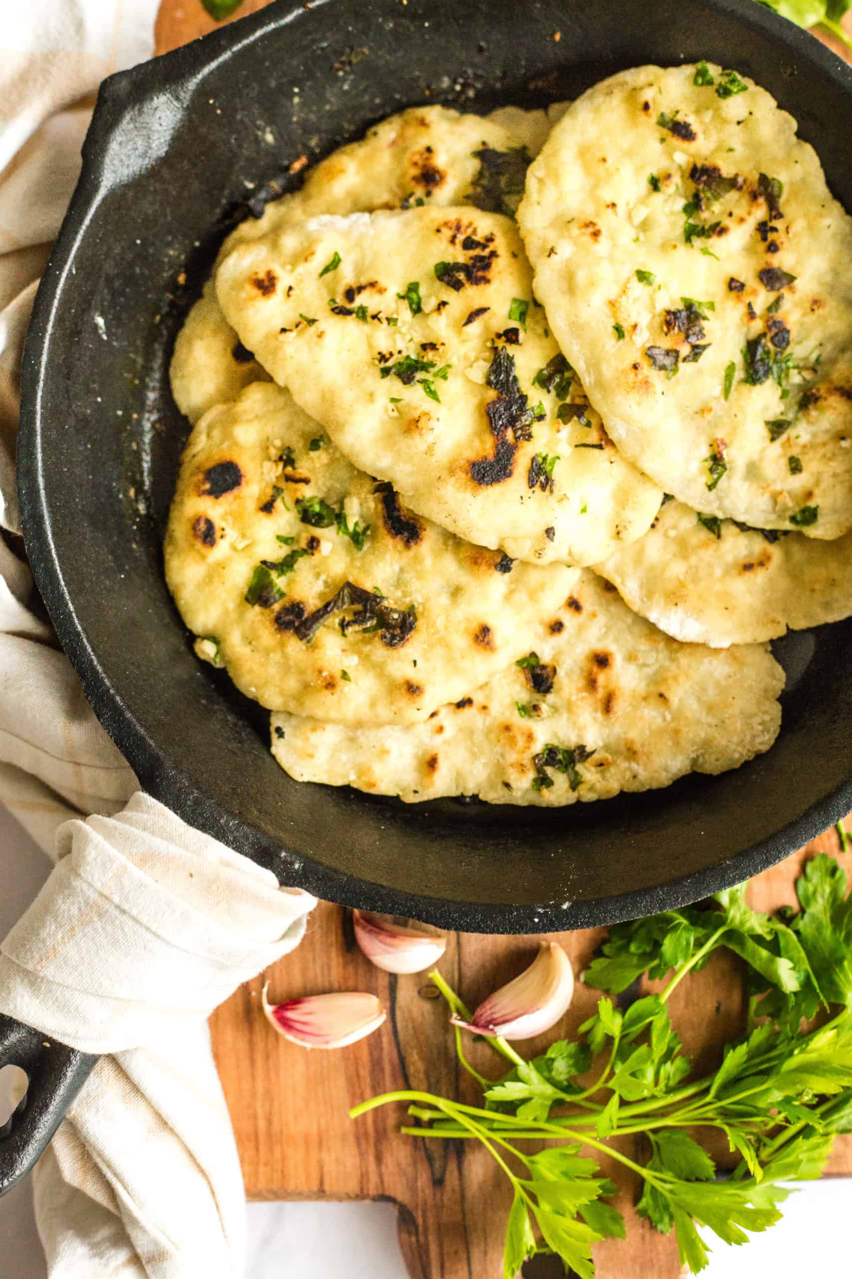 Gluten free naan bread in a cast iron skillet on a wooden board