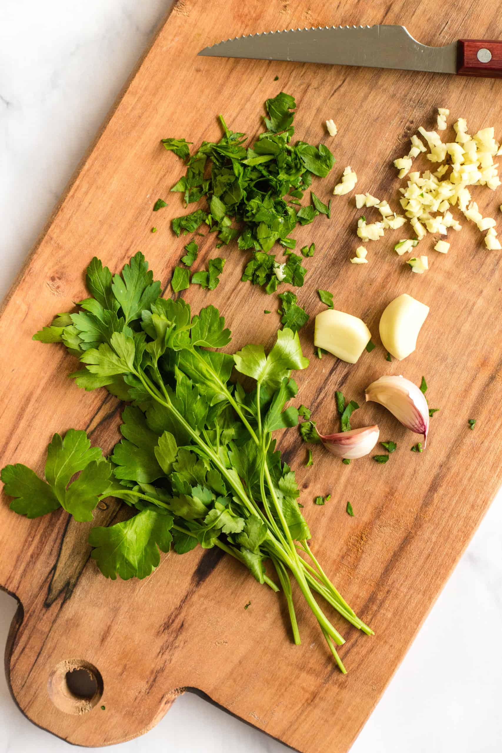 Fresh garlic and parsley on the chopping board.