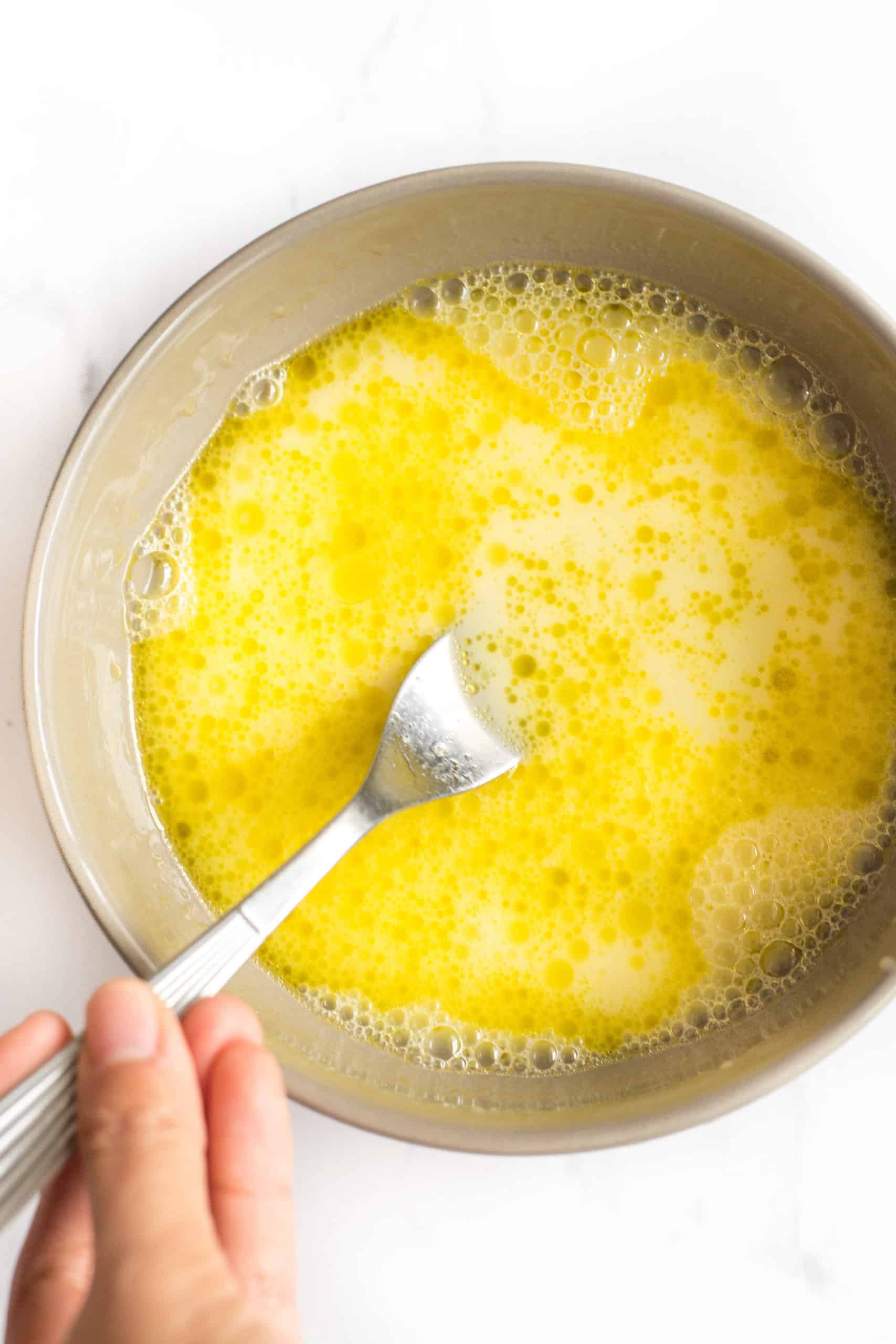 Beating eggs, olive oil, and water in a bowl.