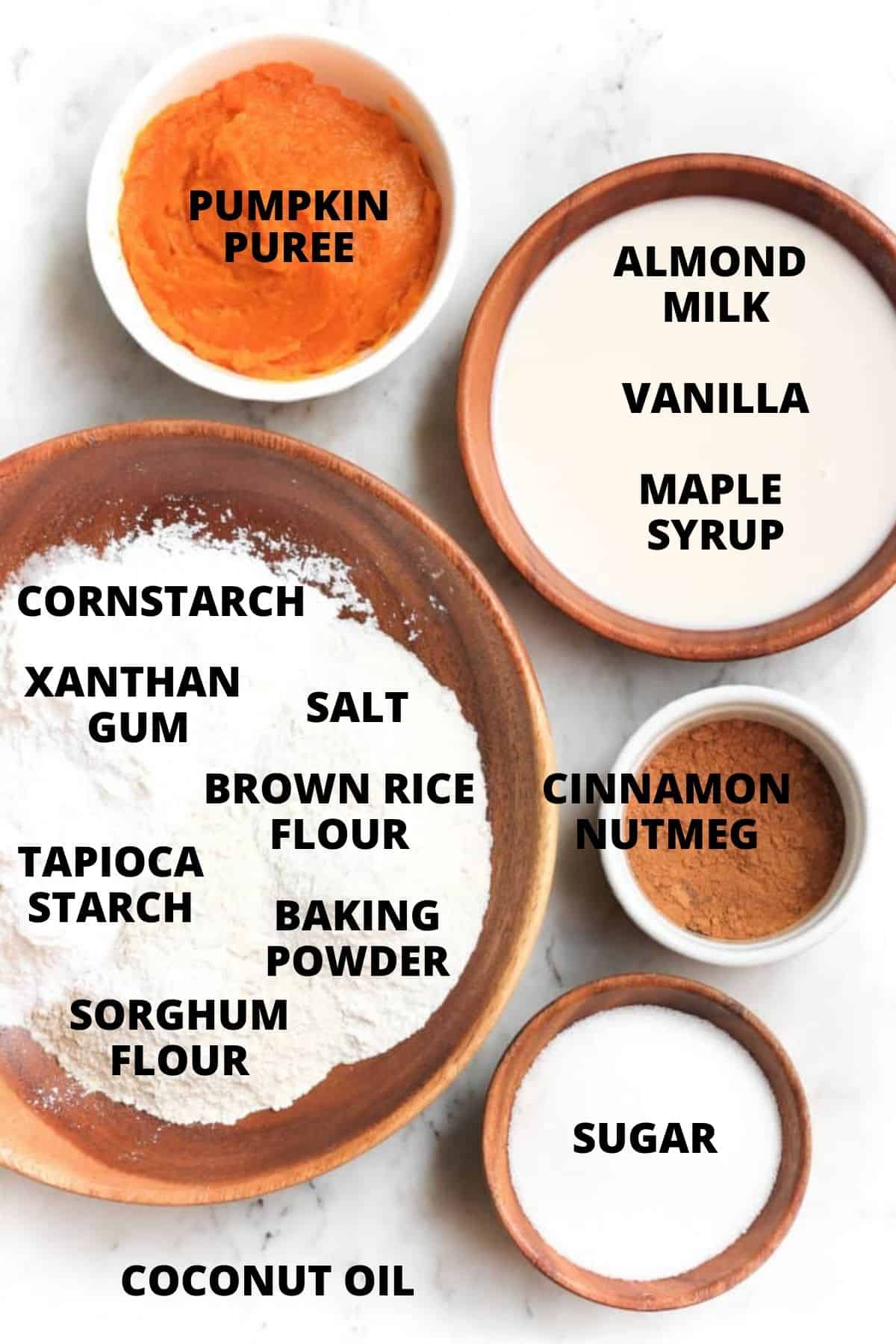 Labeled ingredients for gluten-free pumpkin muffins on a marble board.