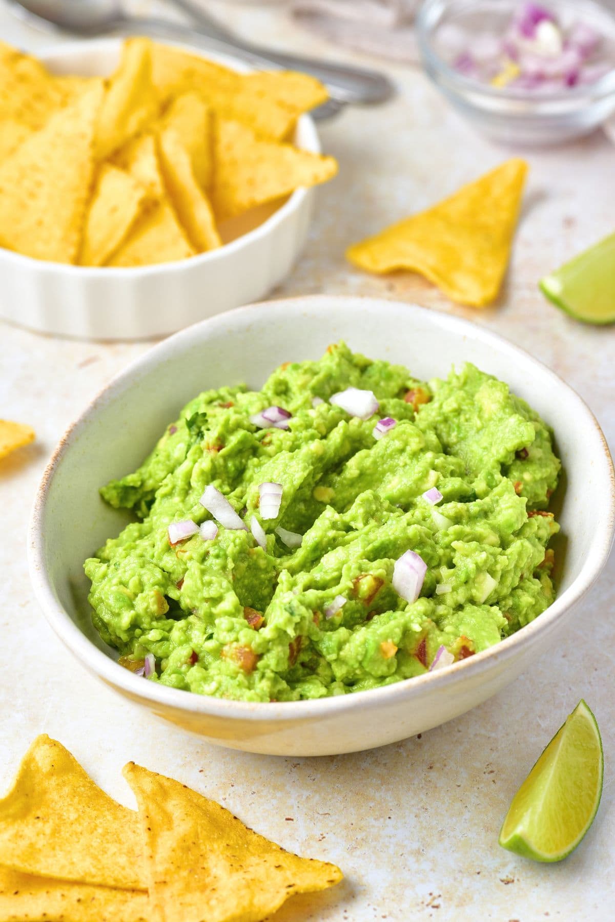 A bowl of homemade guacamole with tortilla chips by the side