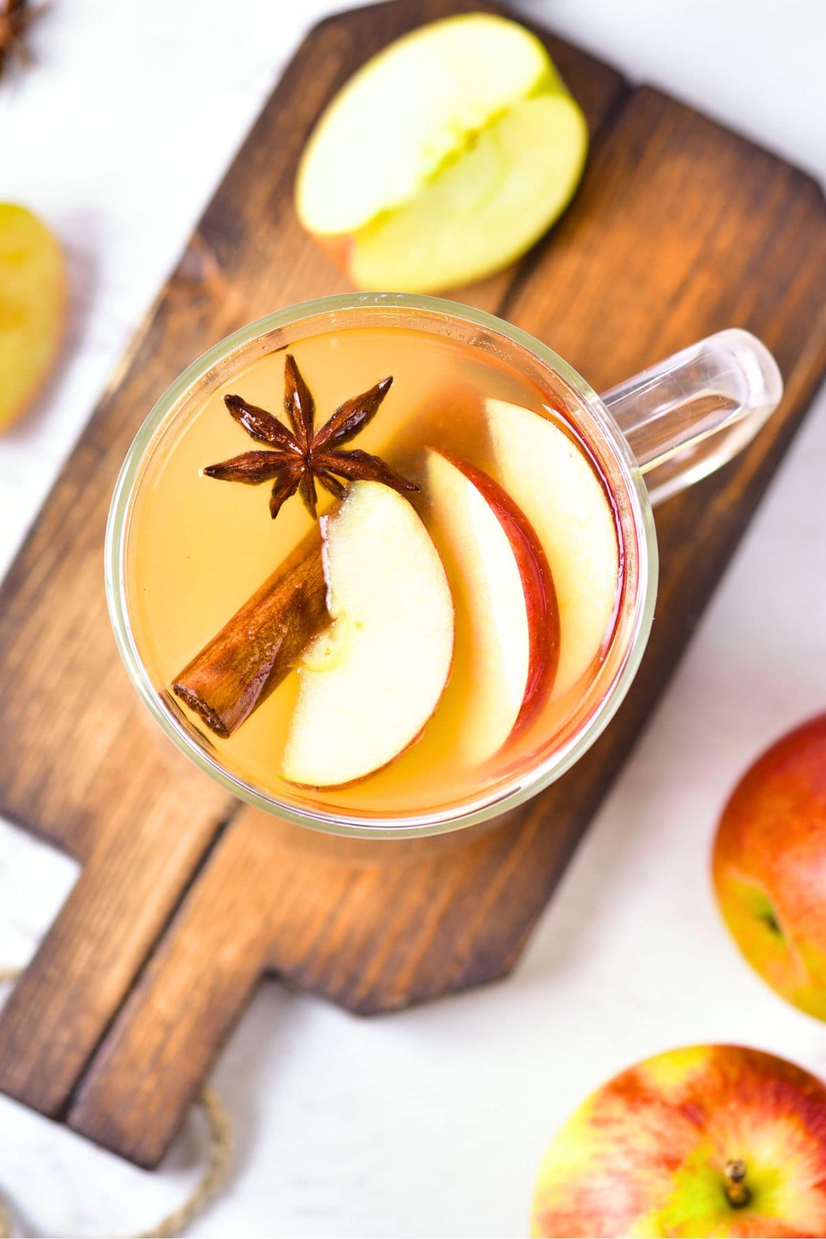 Top down view of a cup of homemade apple cider on a wooden board.