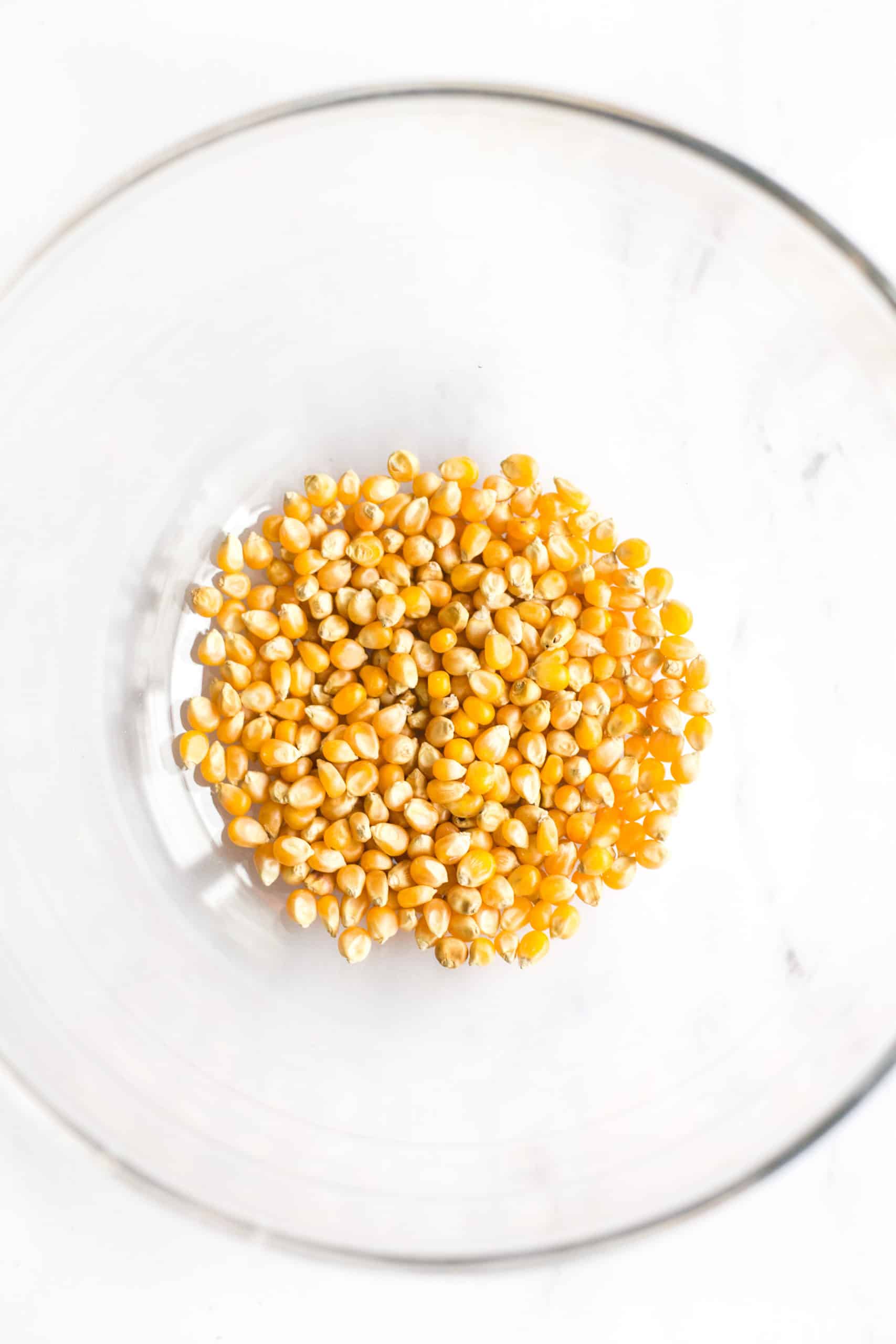 Yellow popcorn kernels in a glass pyrex bowl ready to be popped in the microwave