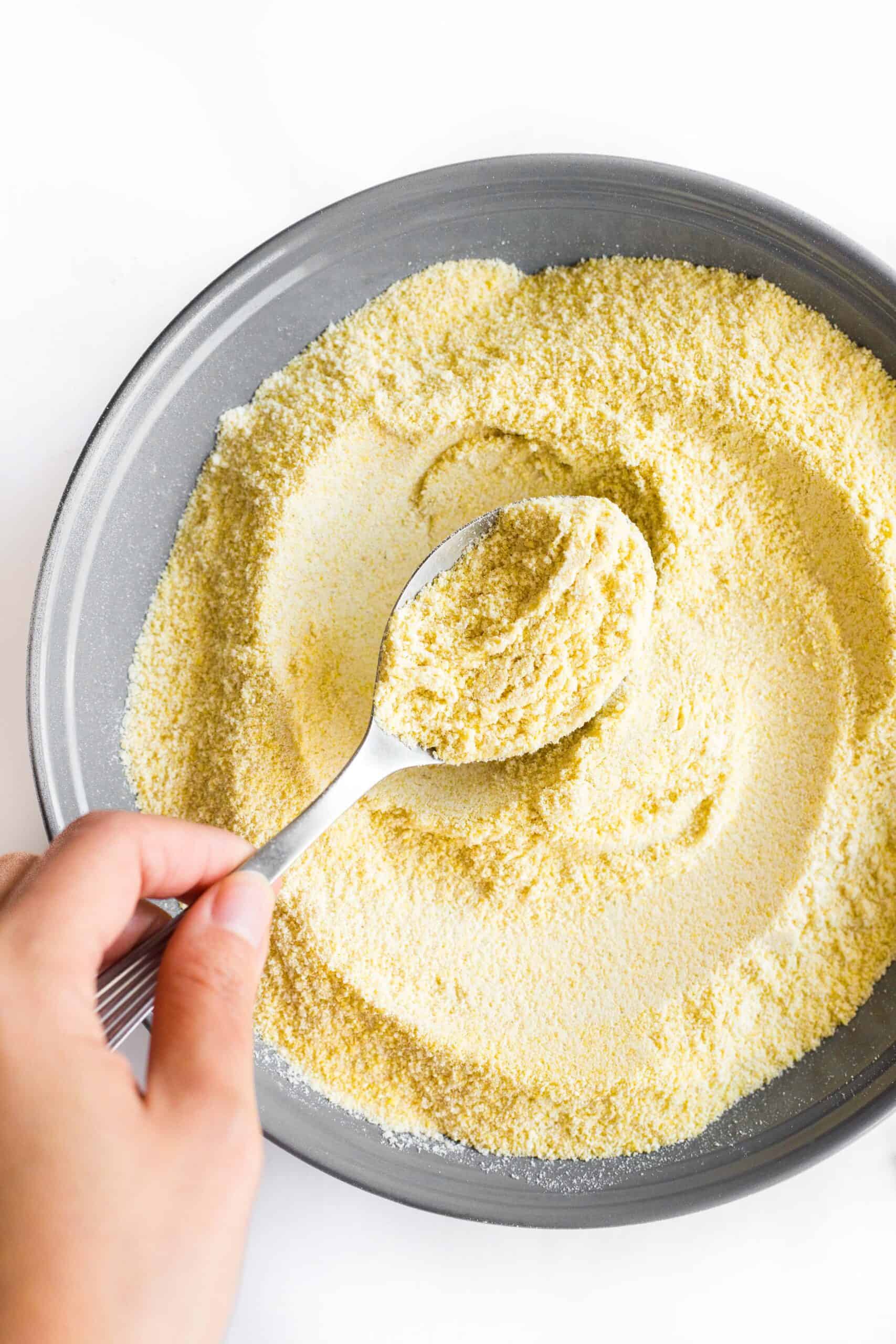 Hand holding up a spoonful of homemade millet flour.