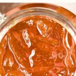 Top down view of an open jar of orange marmalade.