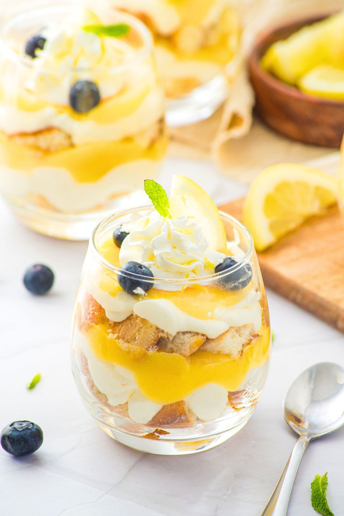 Up close view of lemon dessert cups topped with whipped cream and blueberries.