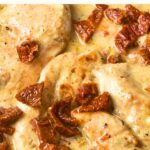 Up close view of chicken breasts topped with sun dried tomatoes.