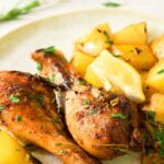 Roasted chicken drumsticks and potatoes on plate.
