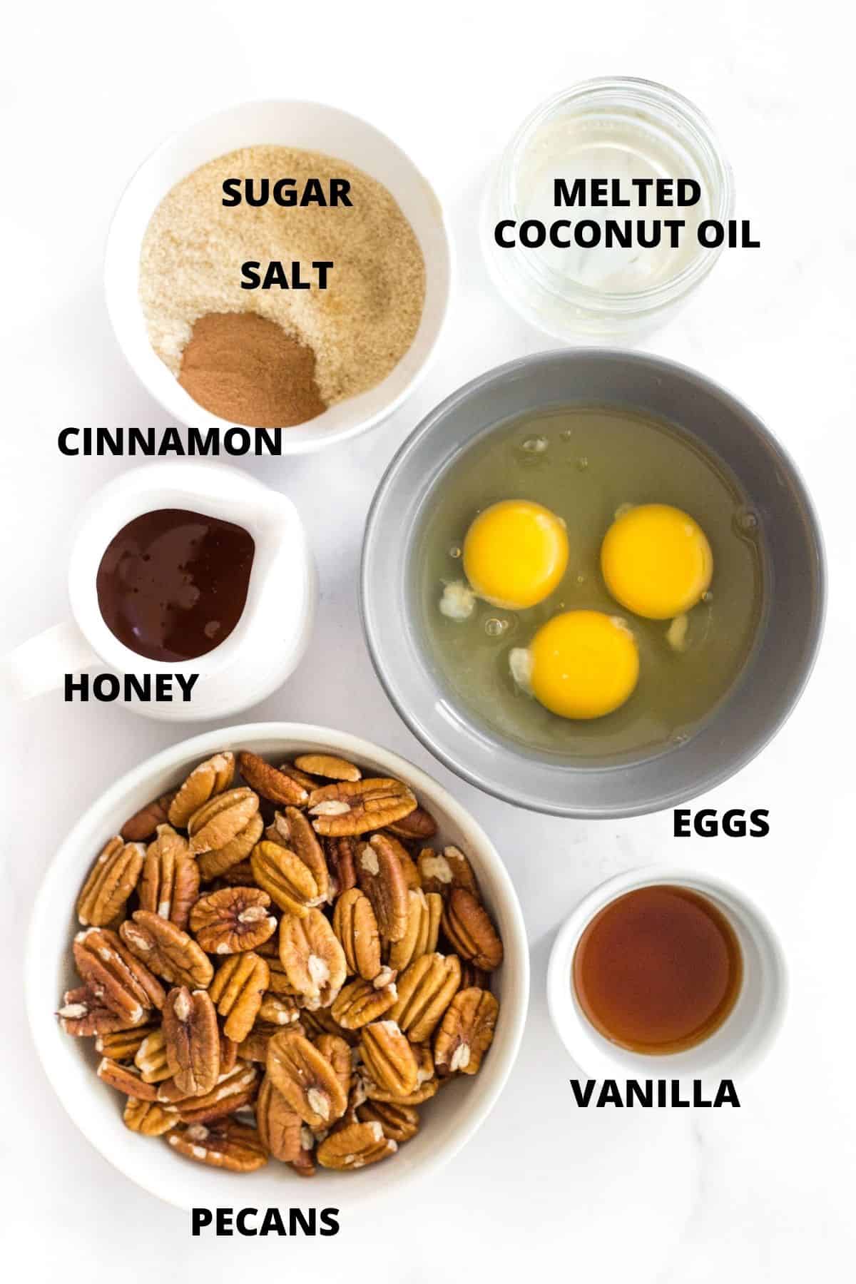 Labeled ingredients for gluten-free pecan pie recipe laid out on marble board.