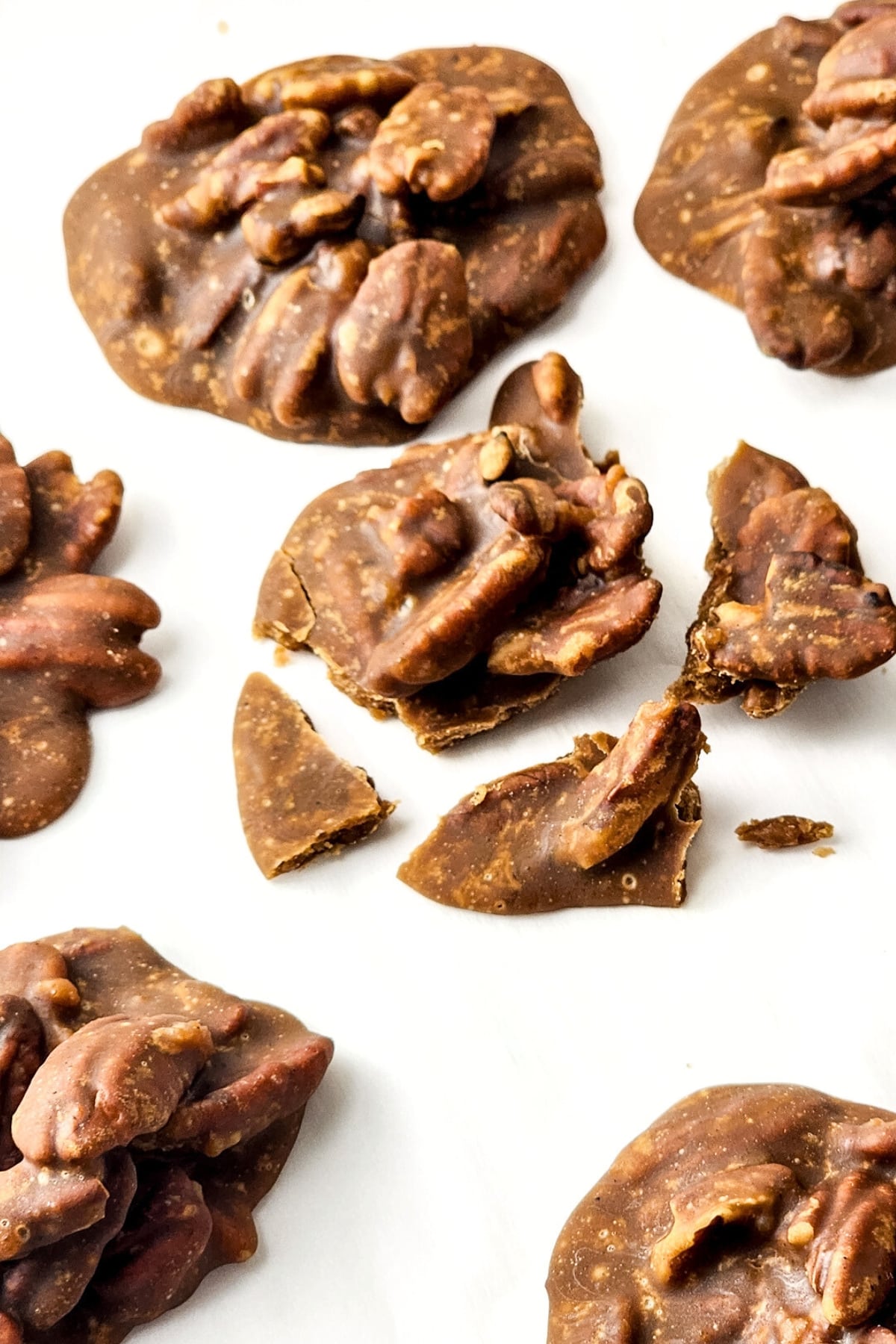 Up close shot of broken pecan pralines on parchment.