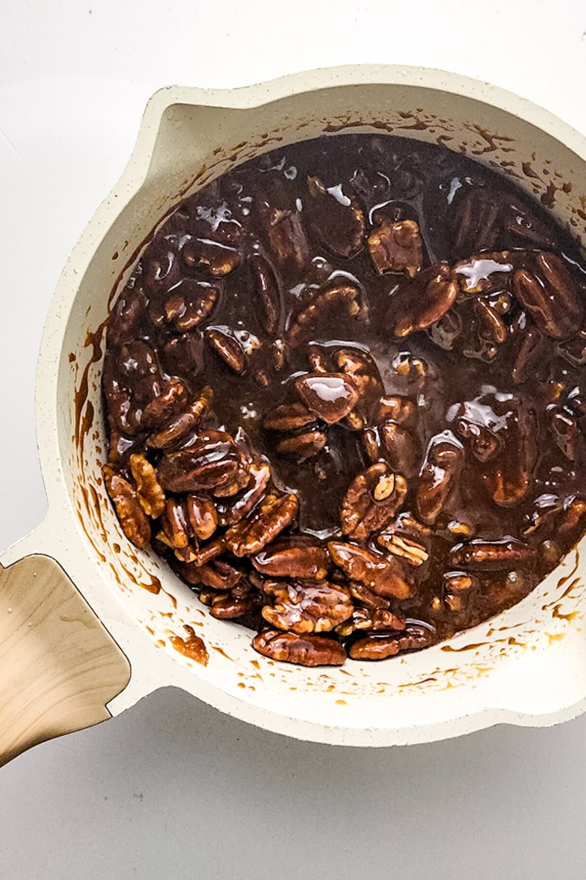 Pecans in caramel mixture in saucepan.