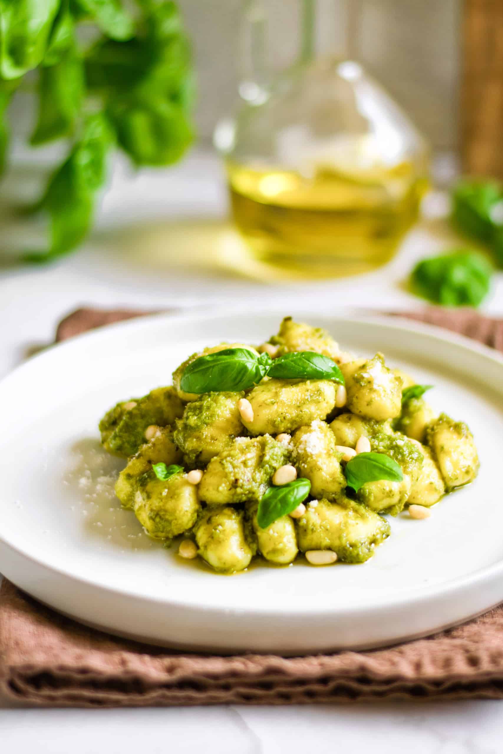 A plate of easy pesto gnocchi on a brown kitchen towel.