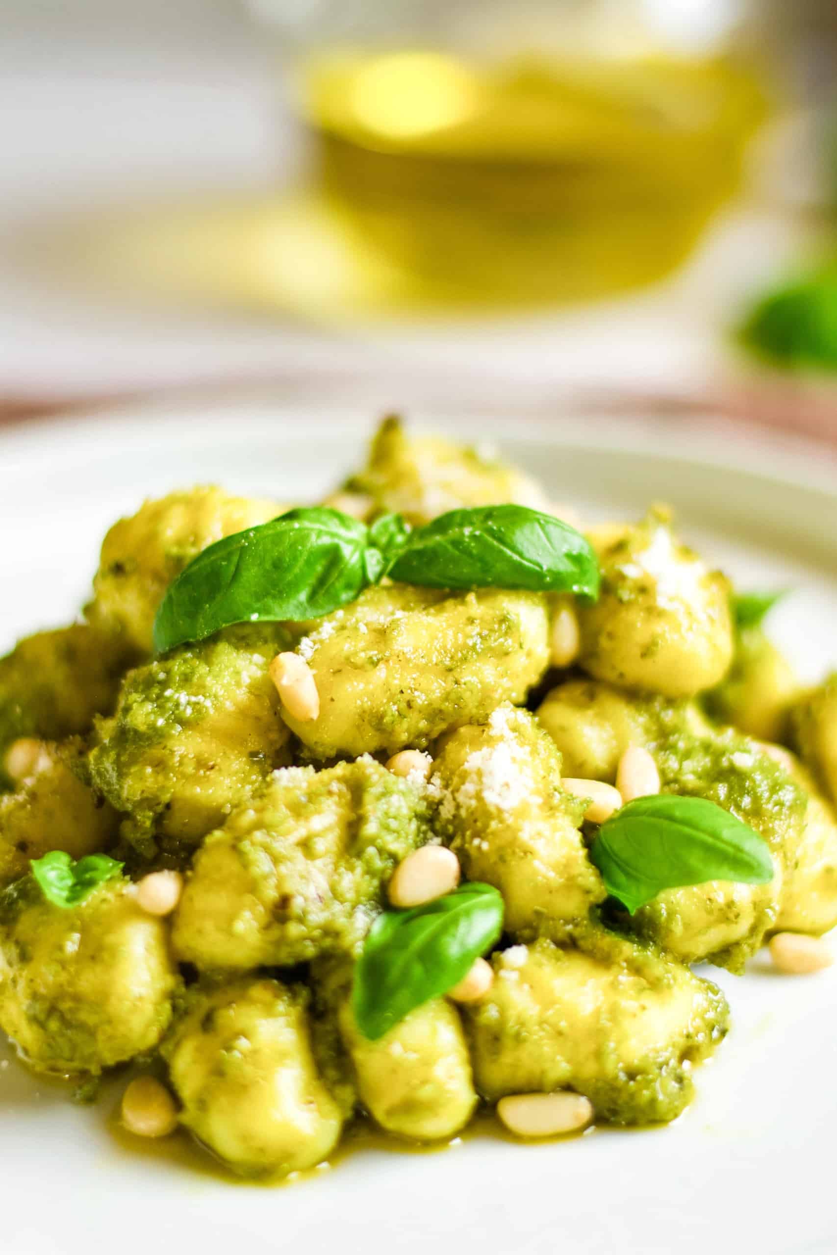 Up close shot of gluten-free pesto gnocchi with basil and pine nuts.