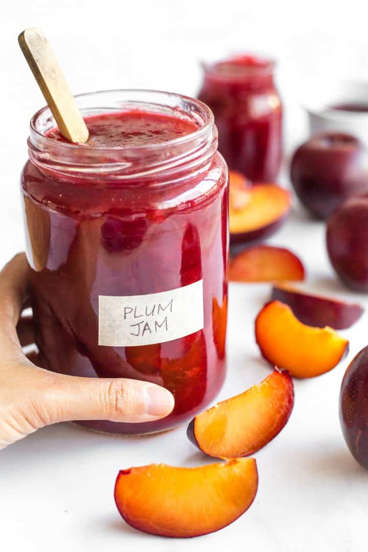 Hand reaching for plum jam