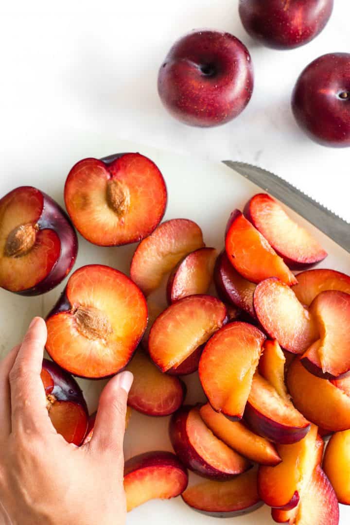 Slicing fresh plums on cutting board