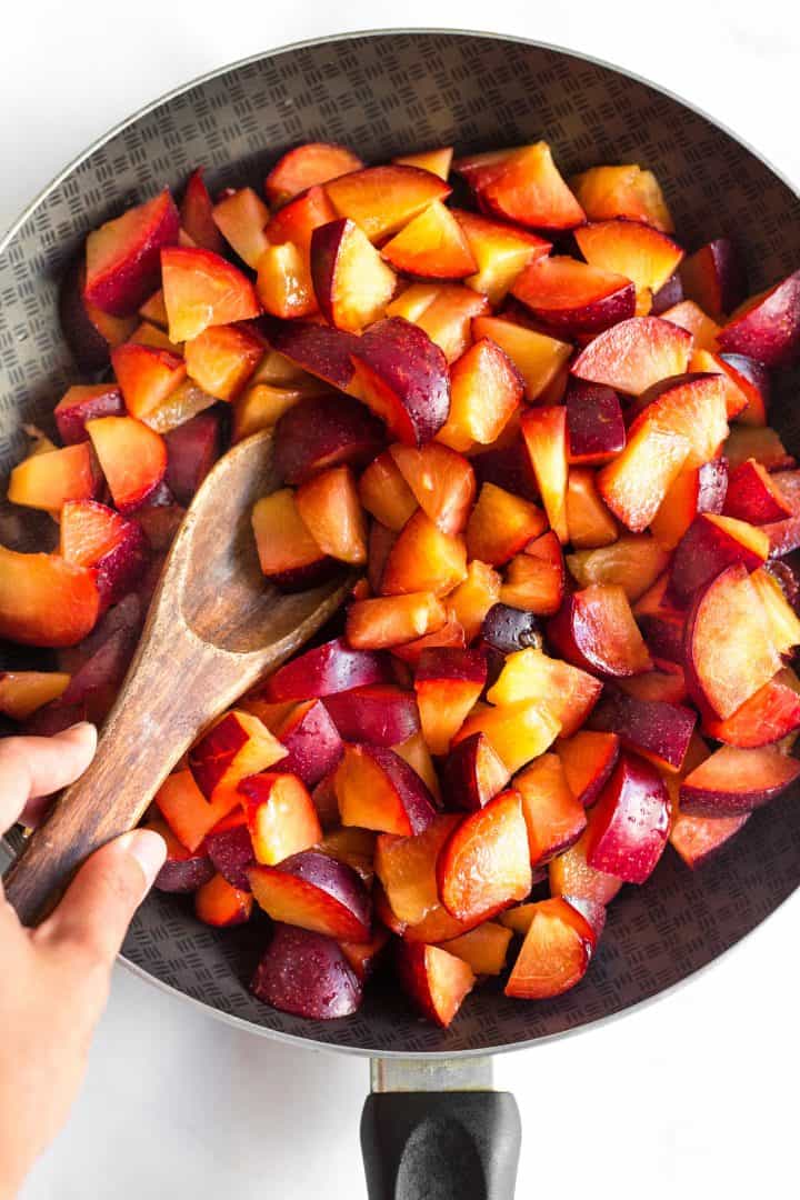 Mixing chopped plums in a skillet