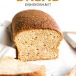 Half-sliced loaf of bread on wooden board.