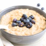Up close view of a bowl of quinoa porridge topped with fresh blueberries