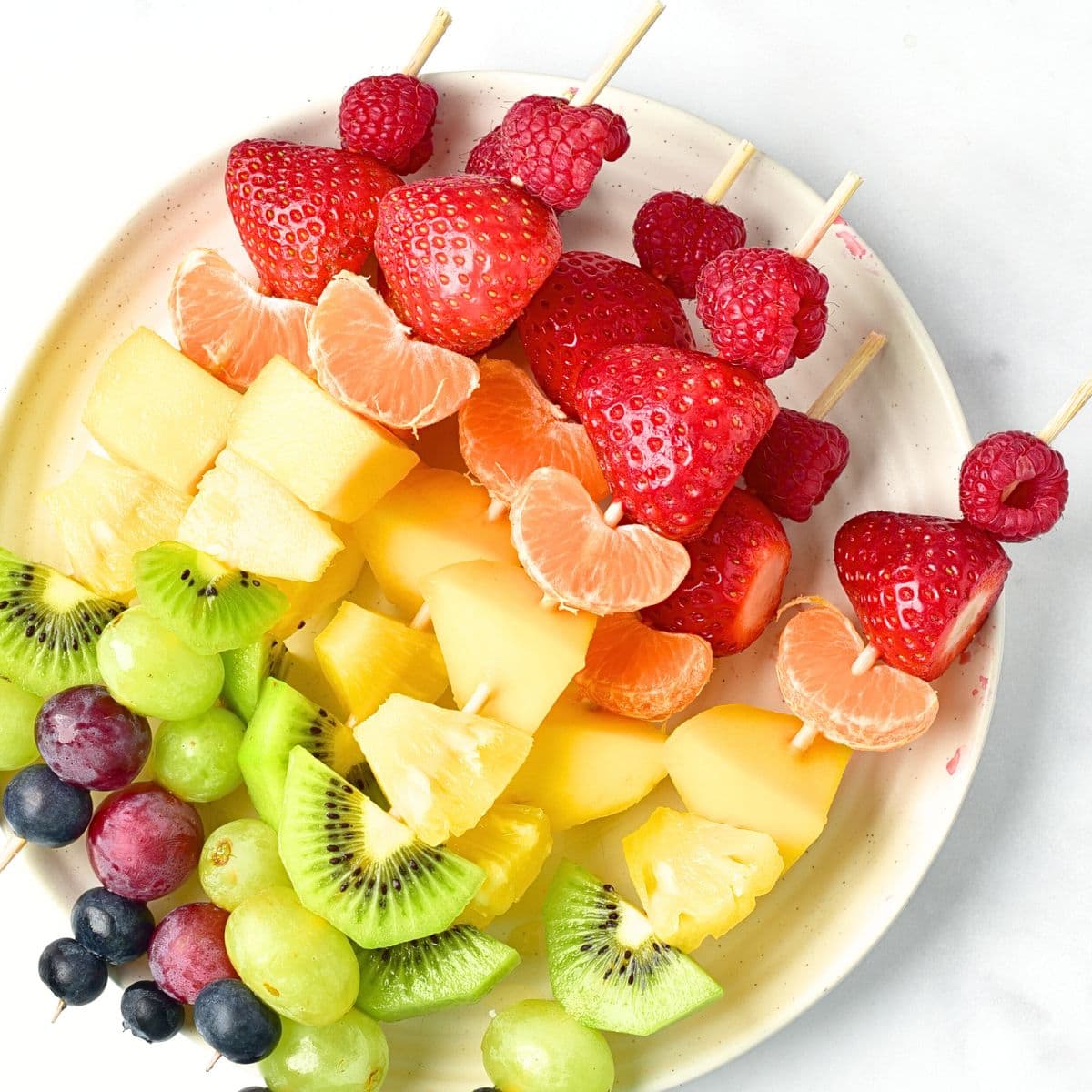 A plate of rainbow fruit skewers