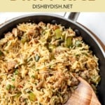 A wooden spoon in a skillet full of Cajun dirty rice.