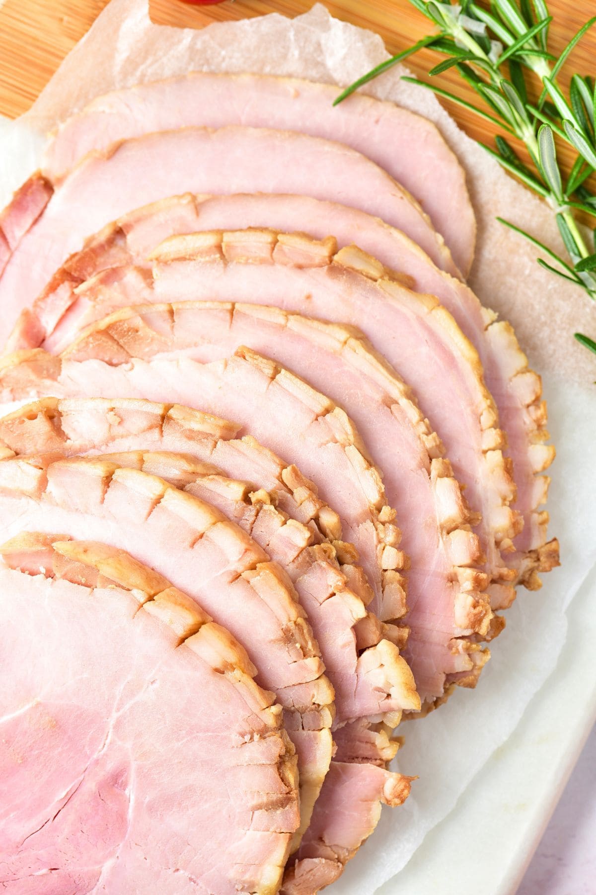 Top down view of sliced ham and rosemary