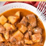 Top down view of bowl of deer stew on red kitchen towel.